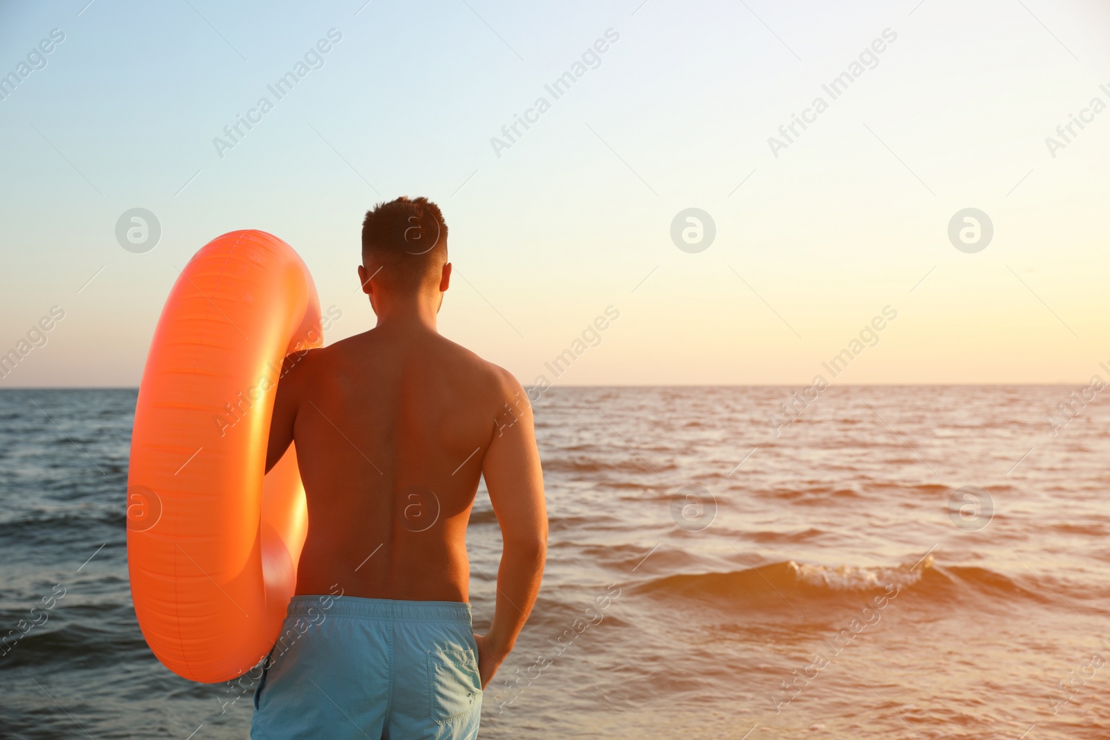 Photo of Young man with inflatable ring on beach