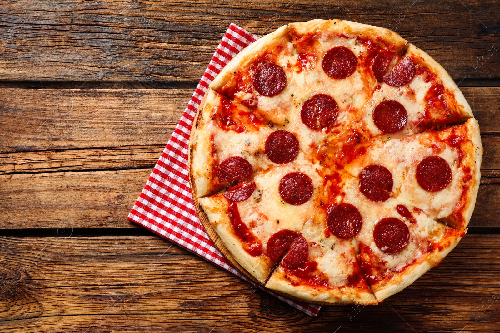 Photo of Hot delicious pepperoni pizza on wooden table, top view