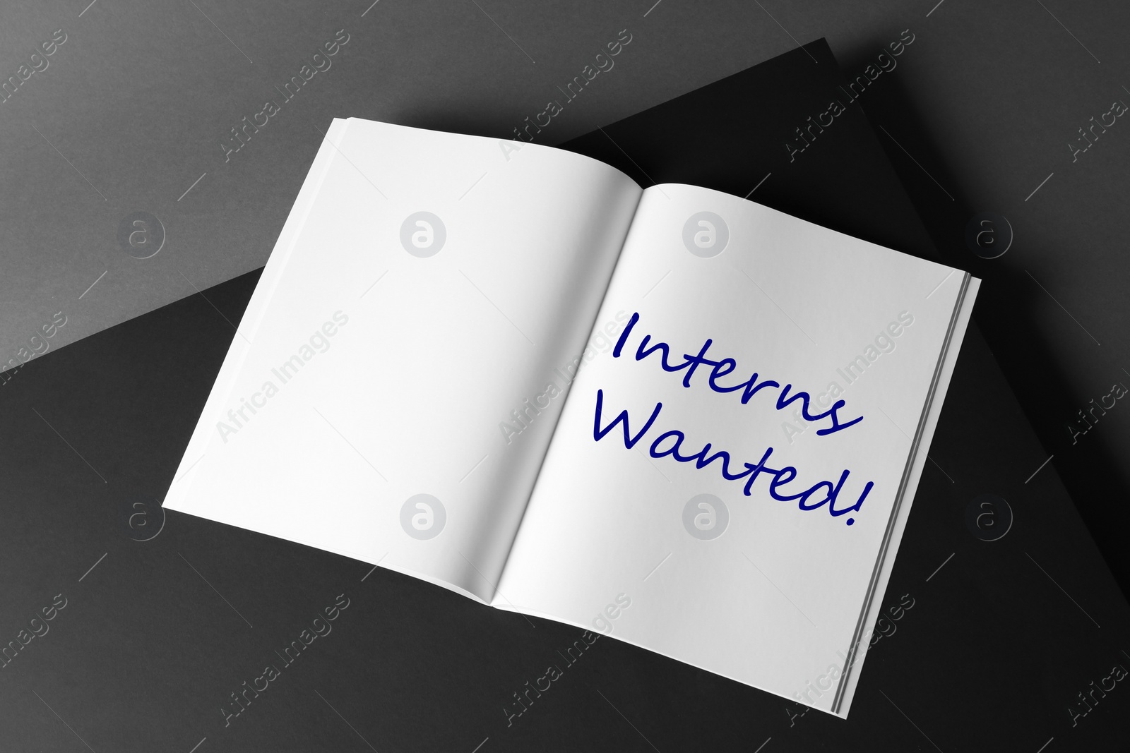 Image of Notebook with text INTERNS WANTED on dark background