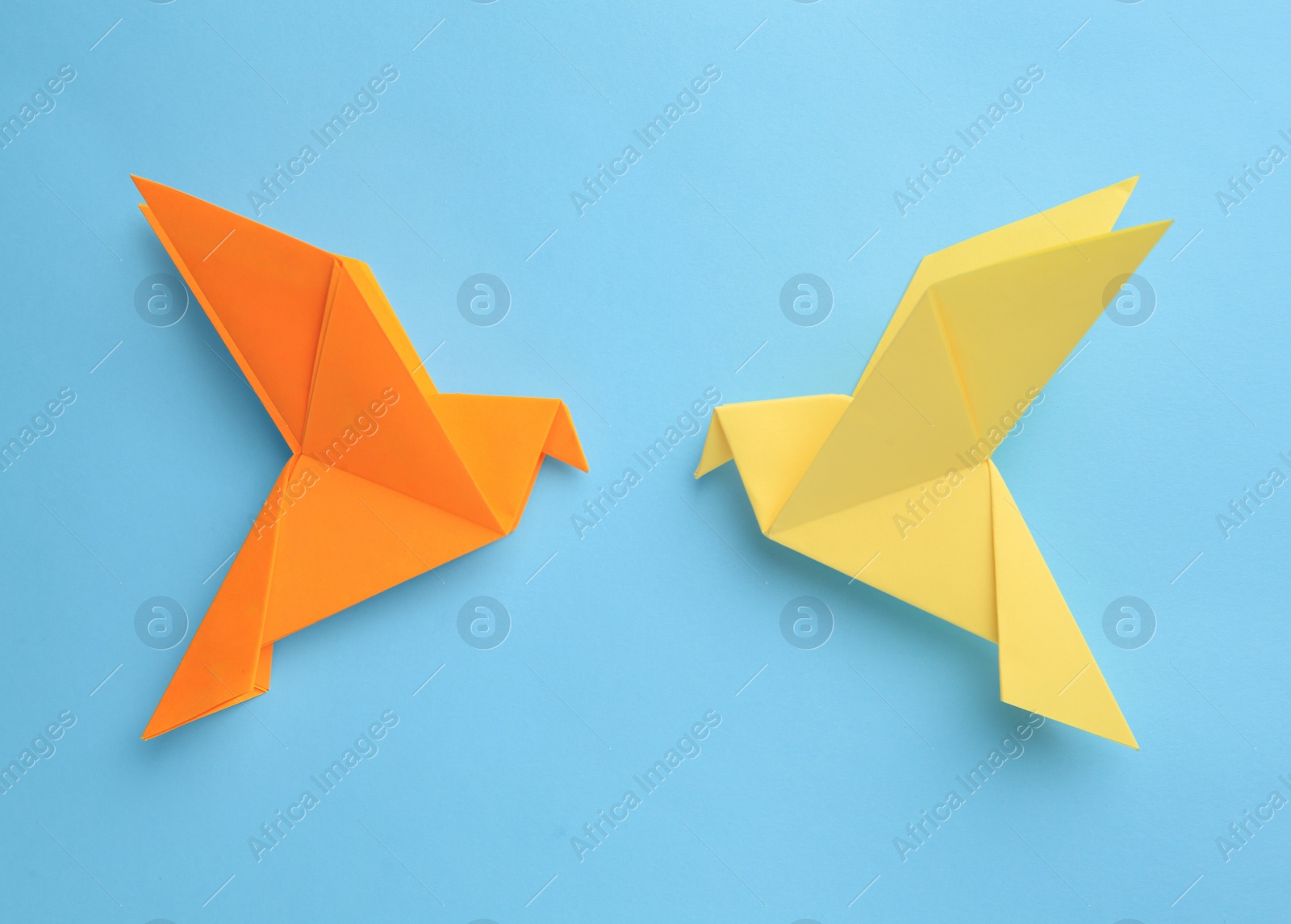 Photo of Origami art. Colorful handmade paper birds on light blue background, flat lay