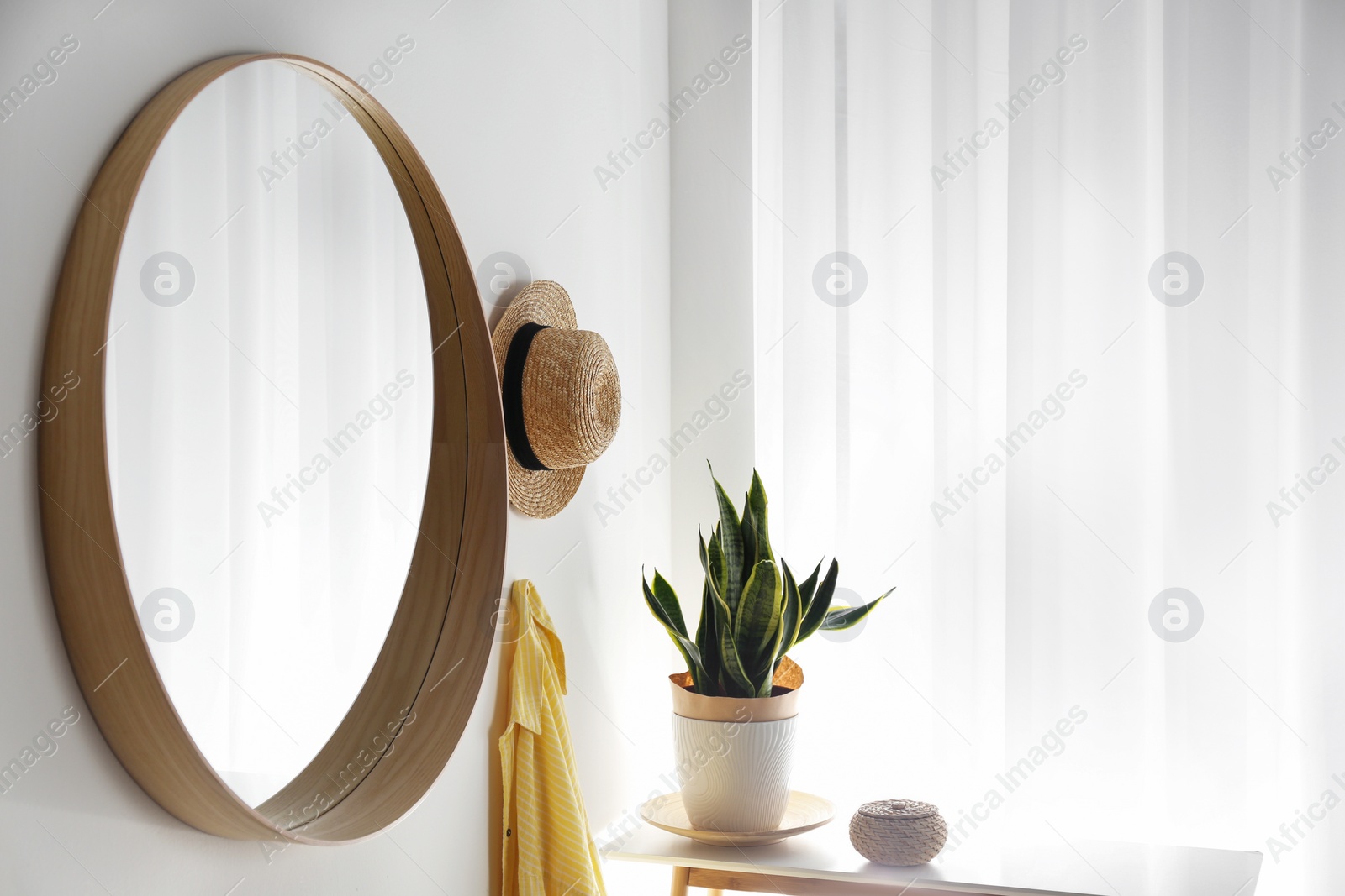 Photo of Round mirror with wooden frame on white wall in light room