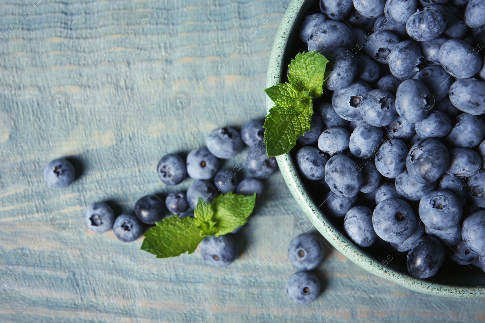 Photo of Flat lay composition with juicy fresh blueberries and green leaves on wooden table