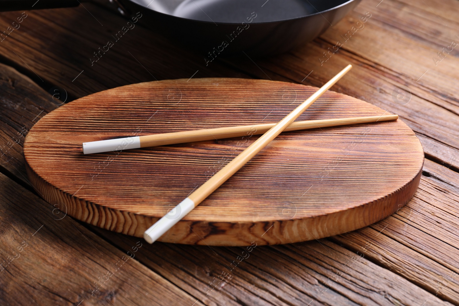 Photo of Serving board with chopsticks on wooden table, closeup