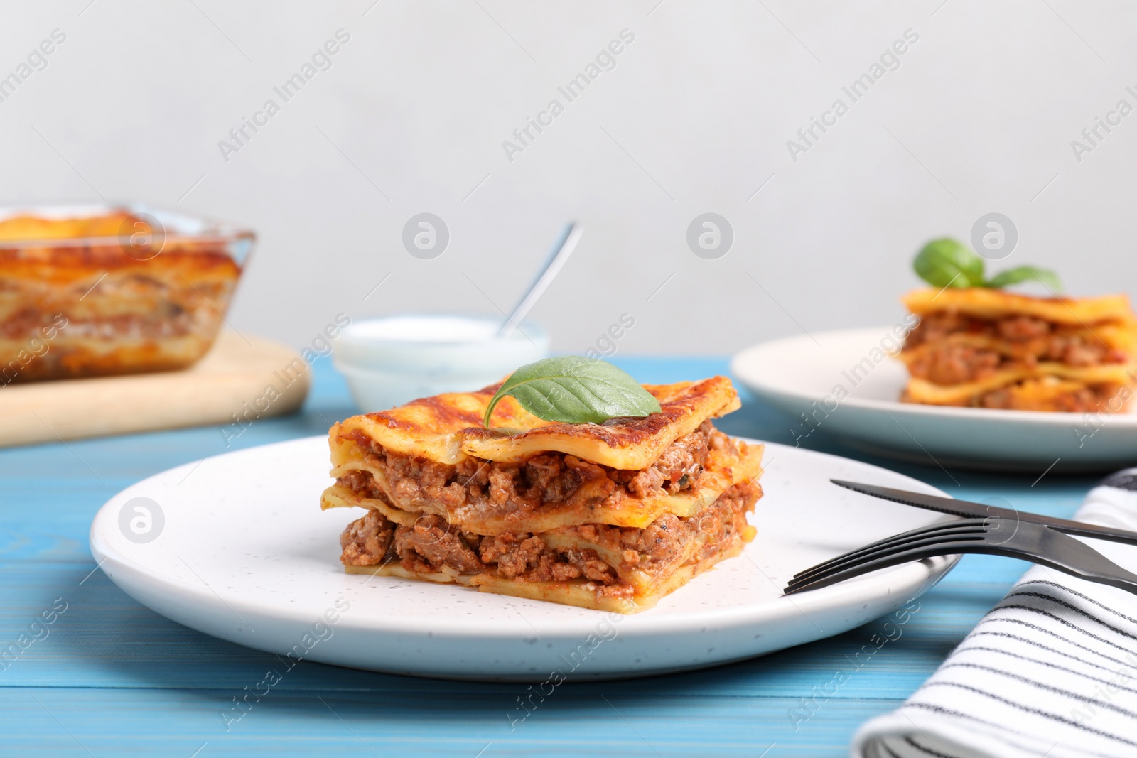 Photo of Tasty cooked lasagna served on light blue table