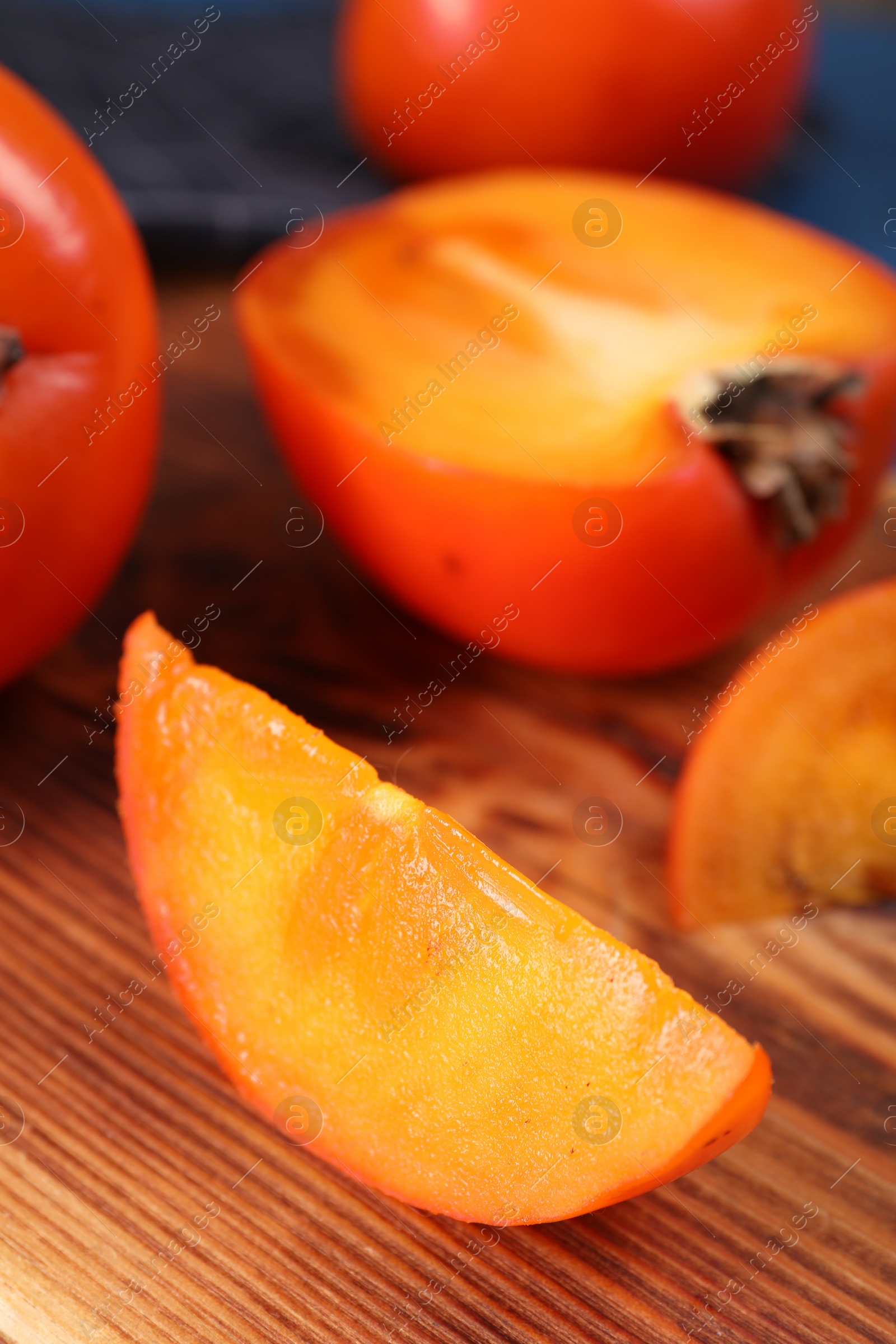 Photo of Delicious cut persimmon on wooden board, closeup