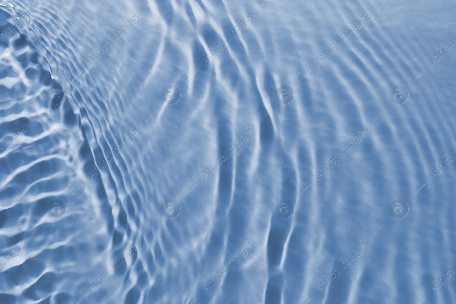 Image of Rippled surface of clear water on light blue background, closeup