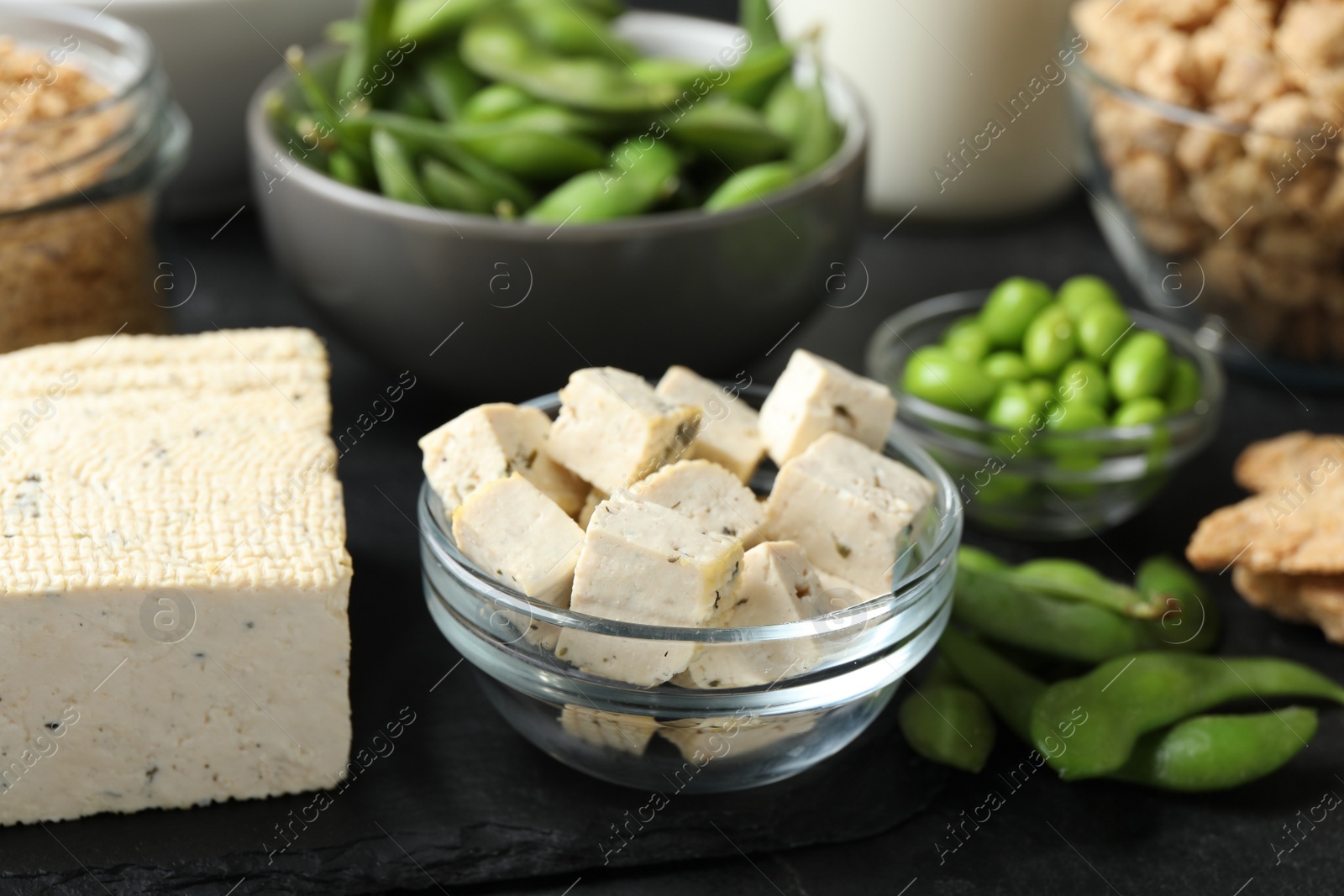 Photo of Delicious tofu and other organic soy products on black table, closeup