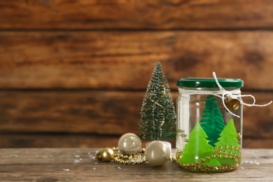 Handmade snow globe and Christmas decorations on wooden table, space for text