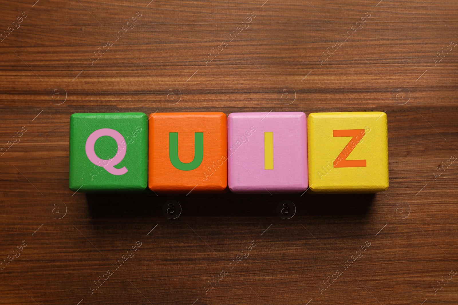 Photo of Colorful cubes with word Quiz on wooden table, flat lay