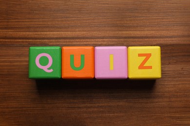 Photo of Colorful cubes with word Quiz on wooden table, flat lay