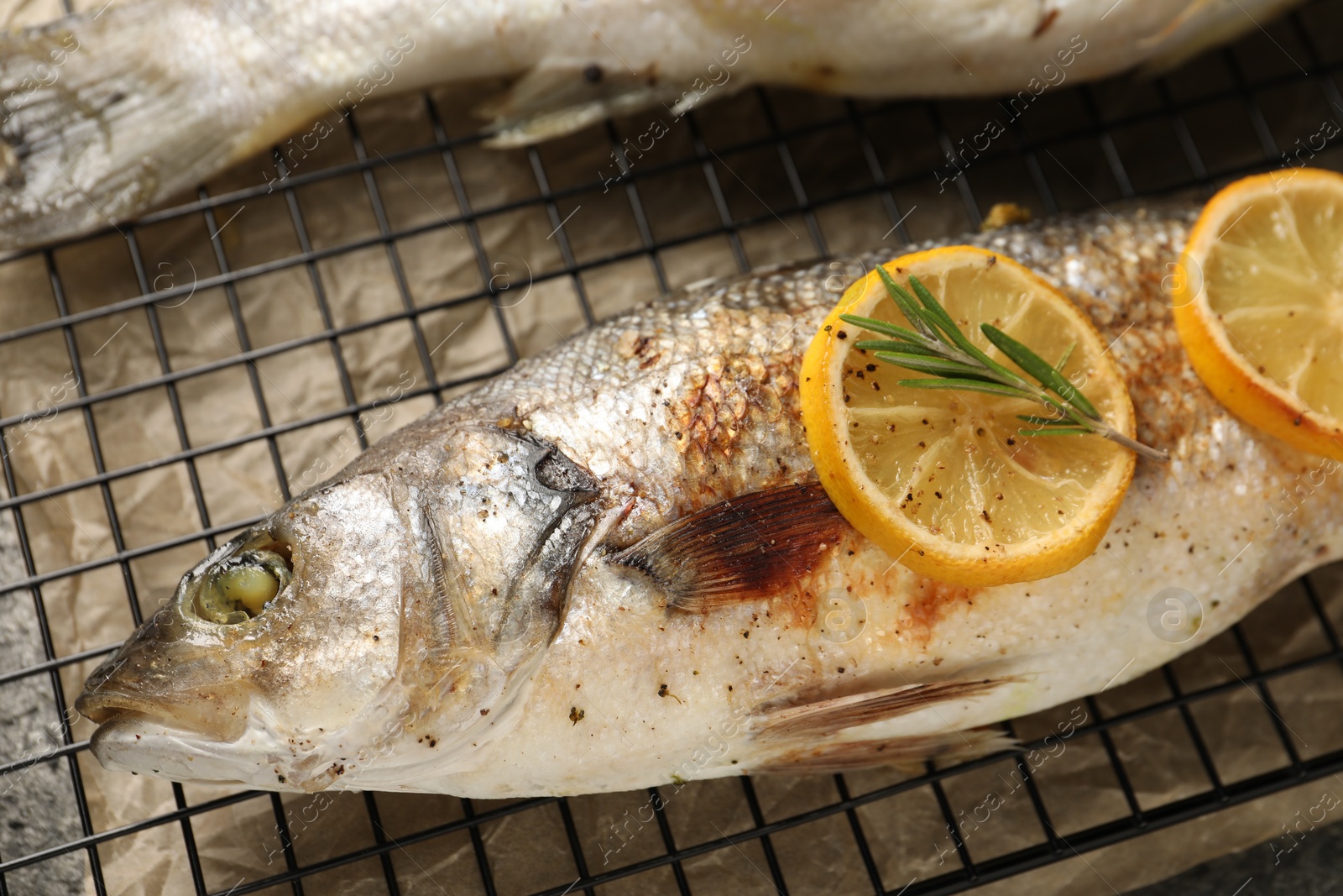 Photo of Baked fish with lemon on cooling rack, flat lay