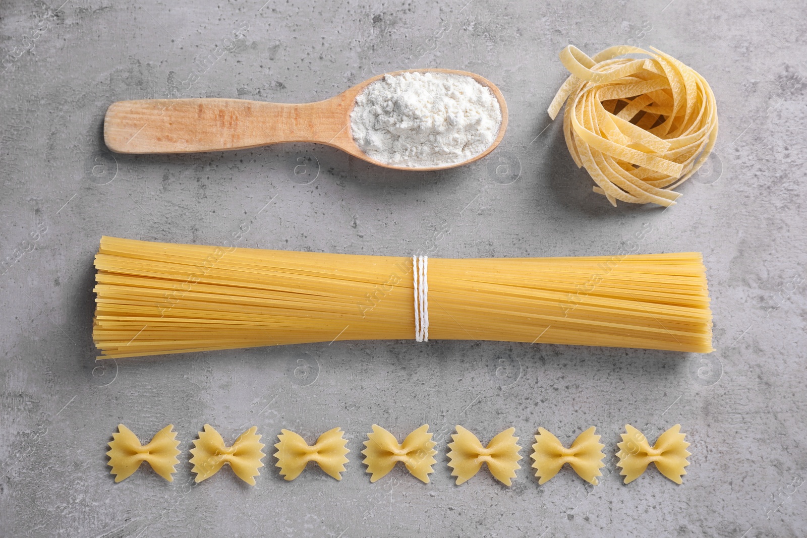 Photo of Flat lay composition with different types of pasta on grey background