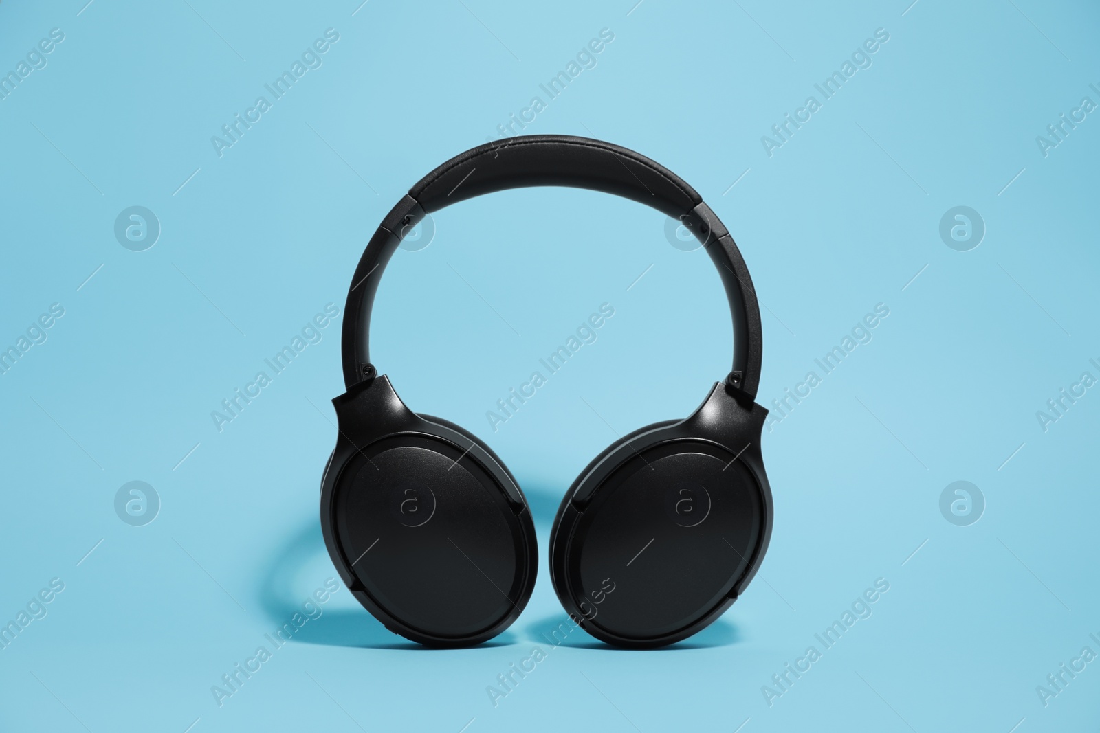 Photo of Modern wireless headphones on light blue background