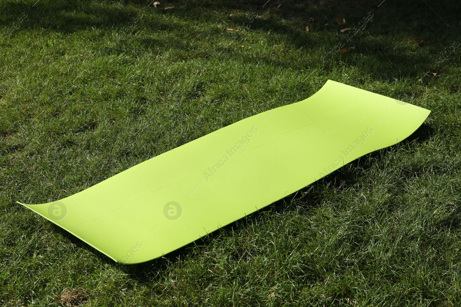 Photo of Bright exercise mat on fresh green grass outdoors