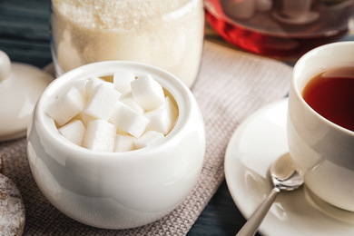 Photo of Refined sugar cubes in ceramic bowl on table