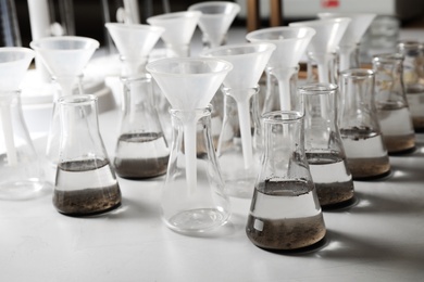 Laboratory glassware with soil extracts and funnels on table