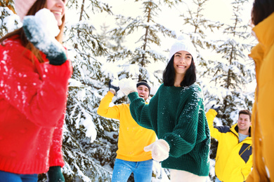 Happy friends playing snowballs outdoors. Winter vacation