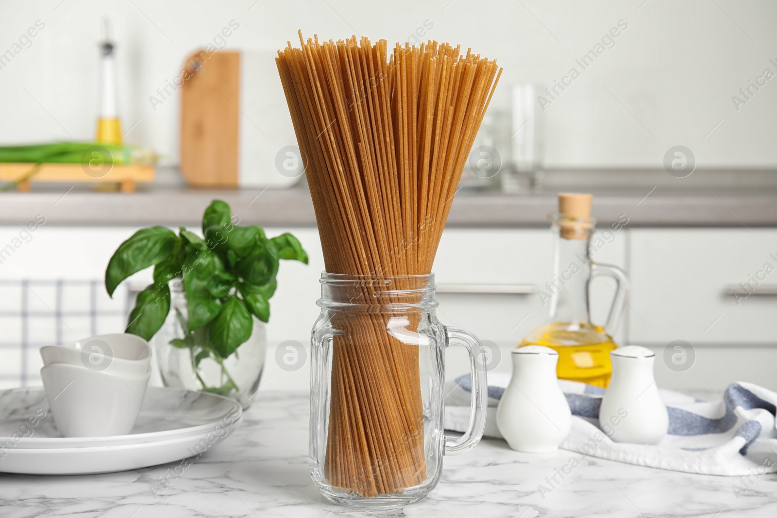 Photo of Uncooked buckwheat noodles on white marble table in kitchen