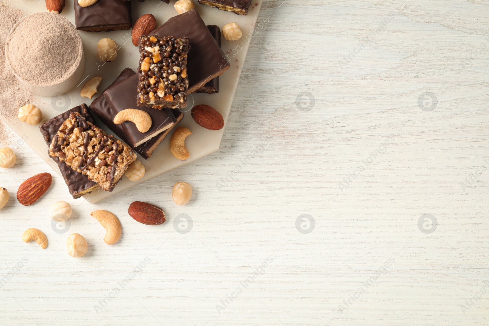 Photo of Different tasty energy bars, nuts and protein powder on white wooden table, flat lay Space for text