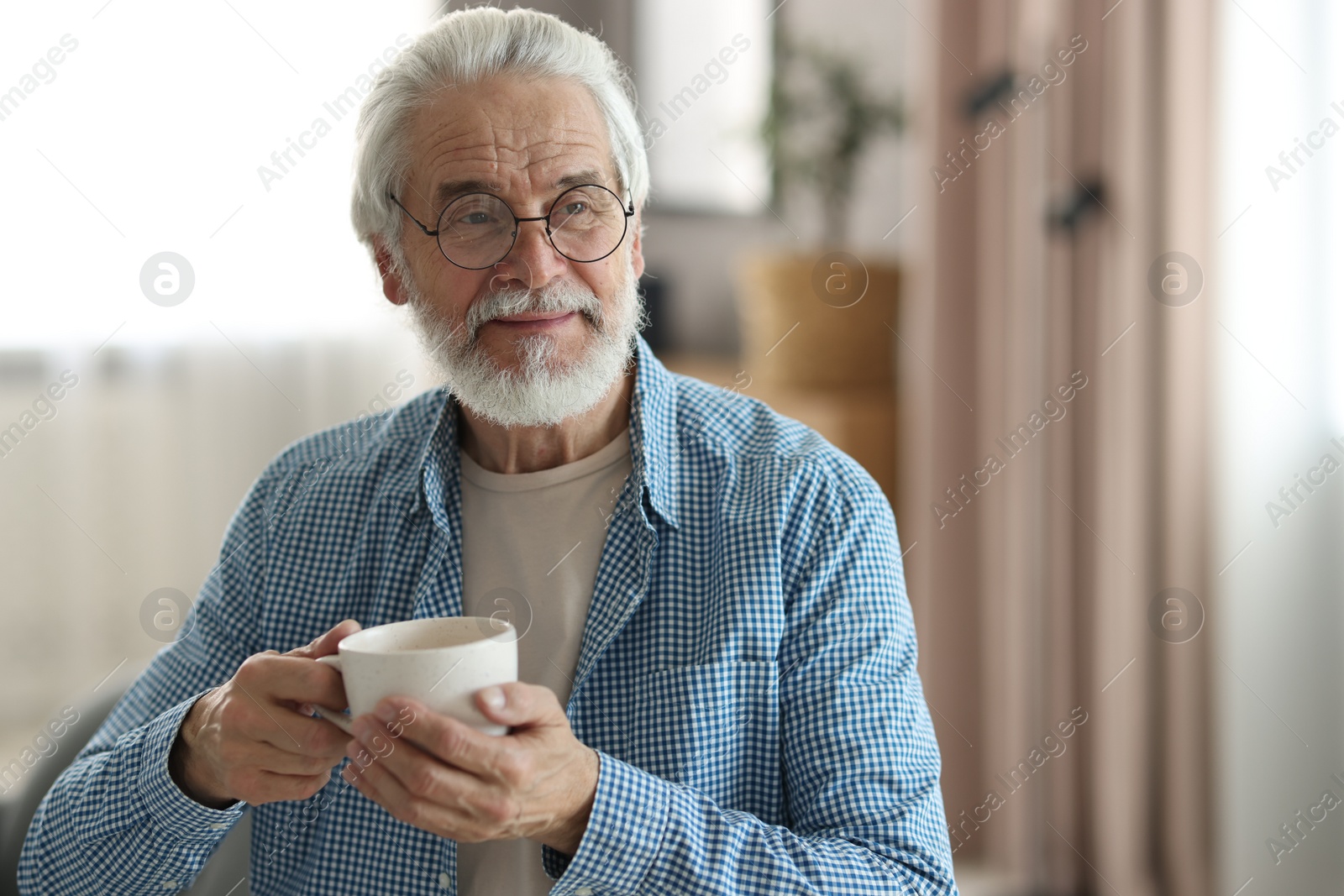 Photo of Portrait of happy grandpa with glasses and cup of drink indoors