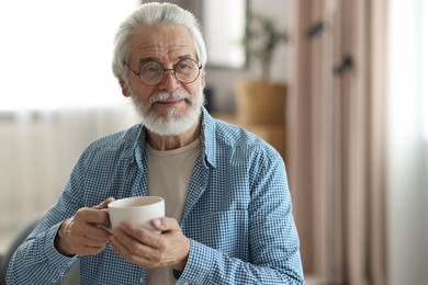 Photo of Portrait of happy grandpa with glasses and cup of drink indoors