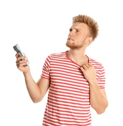 Young man with air conditioner remote suffering from heat on white background