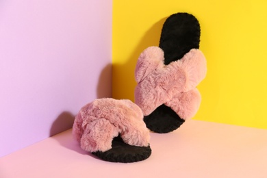 Pair of soft slippers on color background