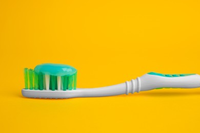 Brush and toothpaste on yellow background, closeup