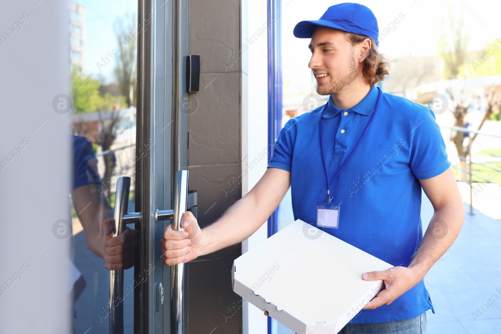 Photo of Male courier with pizza at entrance. Food delivery service