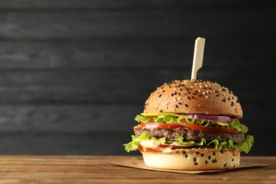 Photo of Burger with delicious patty on wooden table, space for text