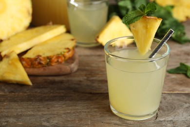 Delicious pineapple juice and fresh fruit on wooden table