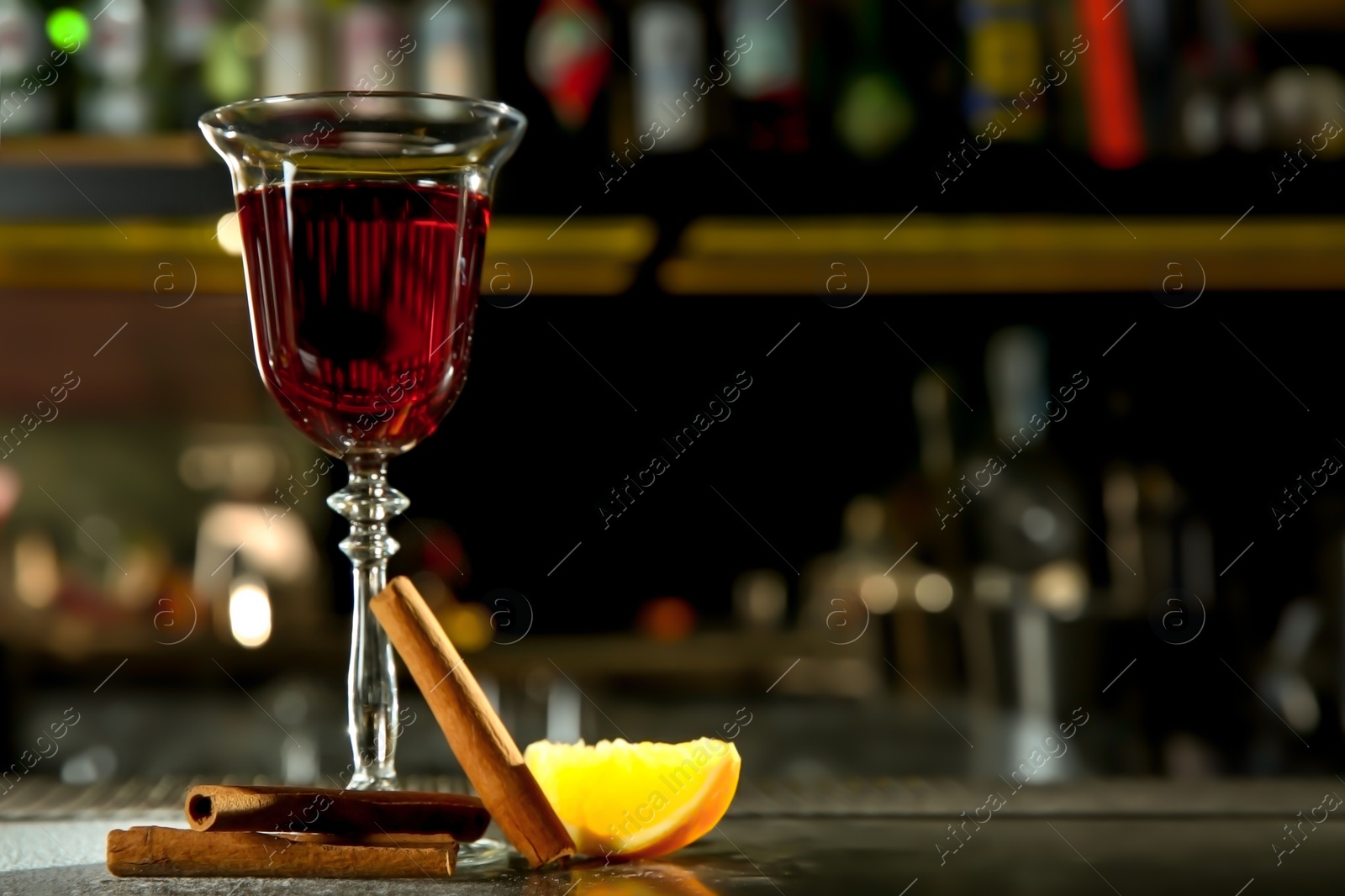 Photo of Fresh red cinnamon whiskey alcoholic cocktail on bar counter. Space for text