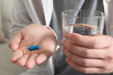 Man with glass of water and pill, closeup