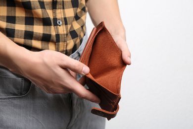 Photo of Man showing empty wallet on light background, closeup