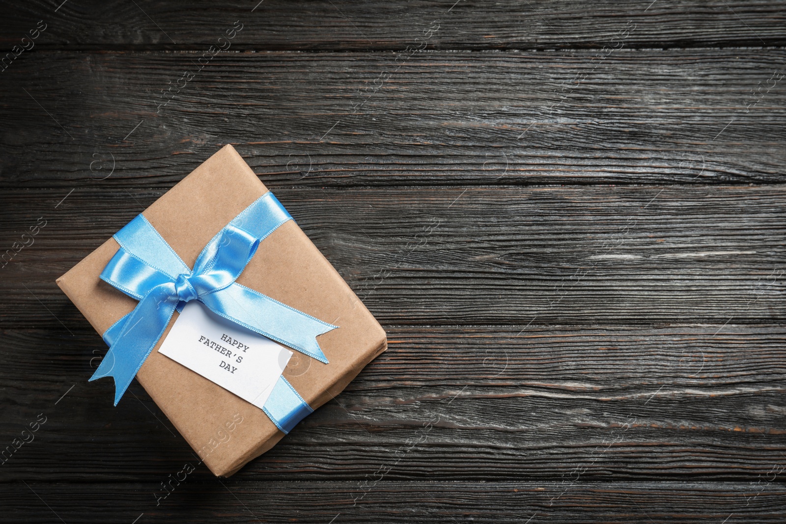 Photo of Gift box with card on wooden background, top view. Father's day celebration