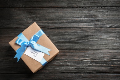 Gift box with card on wooden background, top view. Father's day celebration