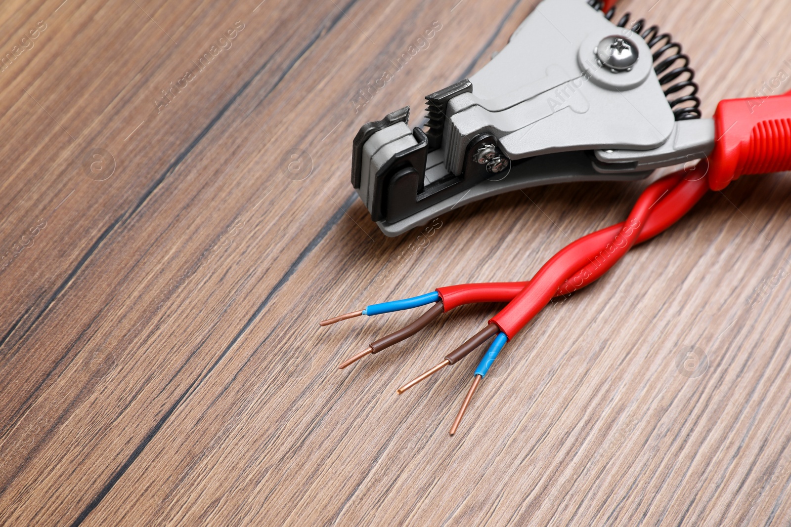 Photo of Cutters and stripped wire on wooden table, closeup. Space for text