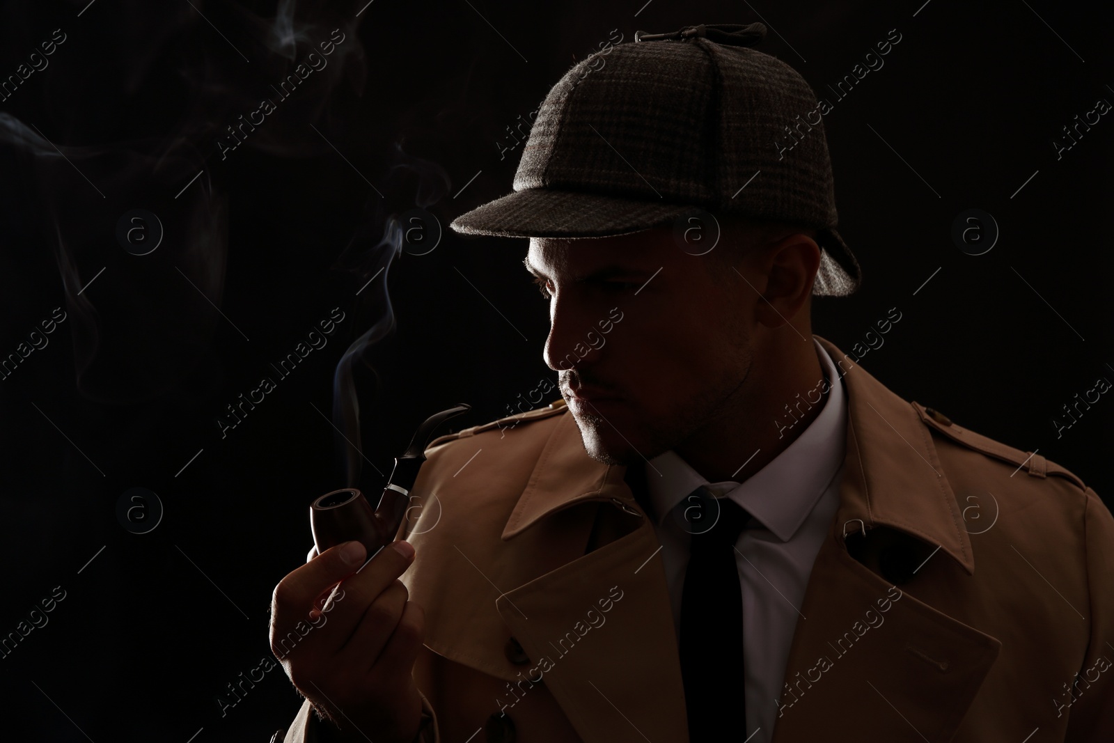Photo of Old fashioned detective smoking pipe on dark background