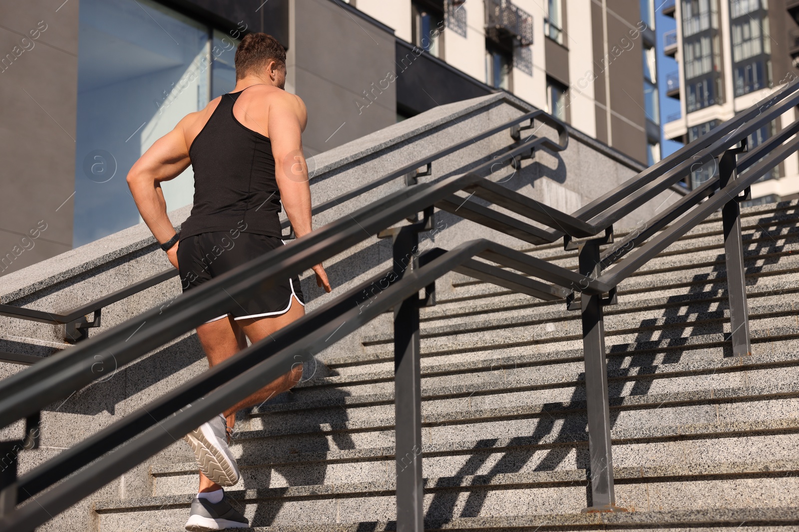 Photo of Man running up stairs outdoors on sunny day