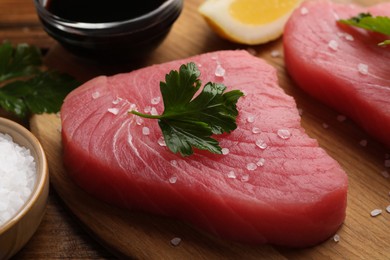 Fresh raw tuna fillet with sea salt and parsley on wooden table, closeup