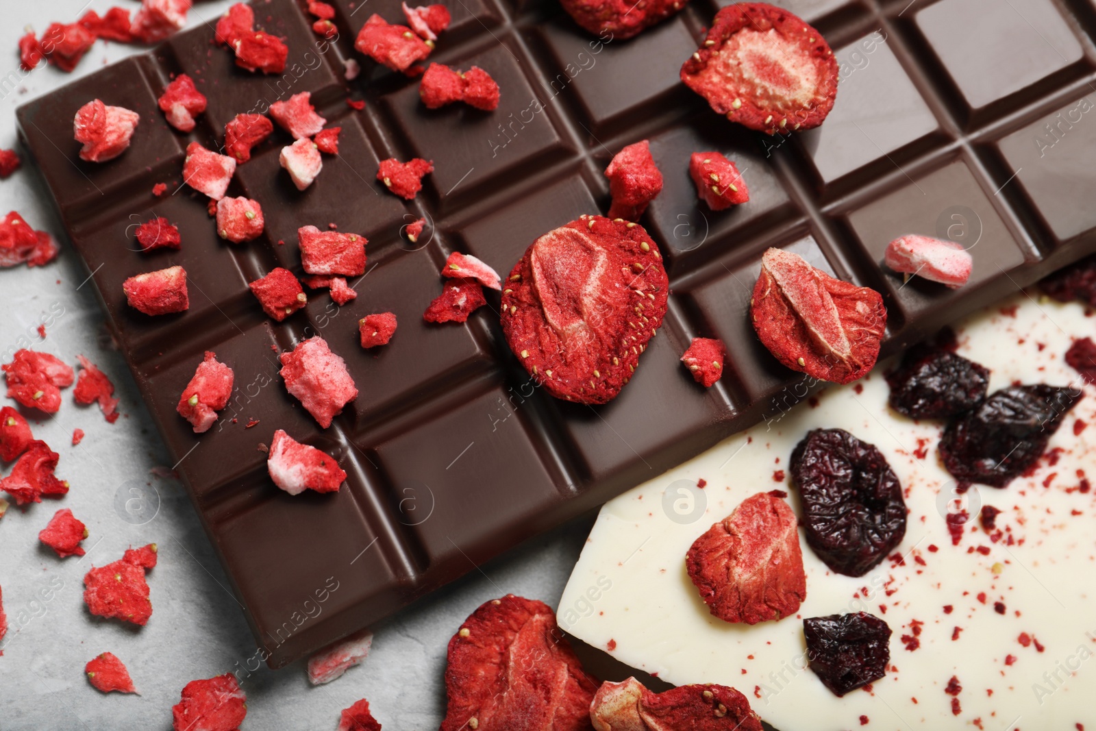 Photo of Different chocolate bars with freeze dried fruits on light marble table, closeup