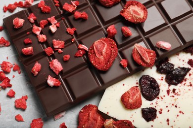 Different chocolate bars with freeze dried fruits on light marble table, closeup