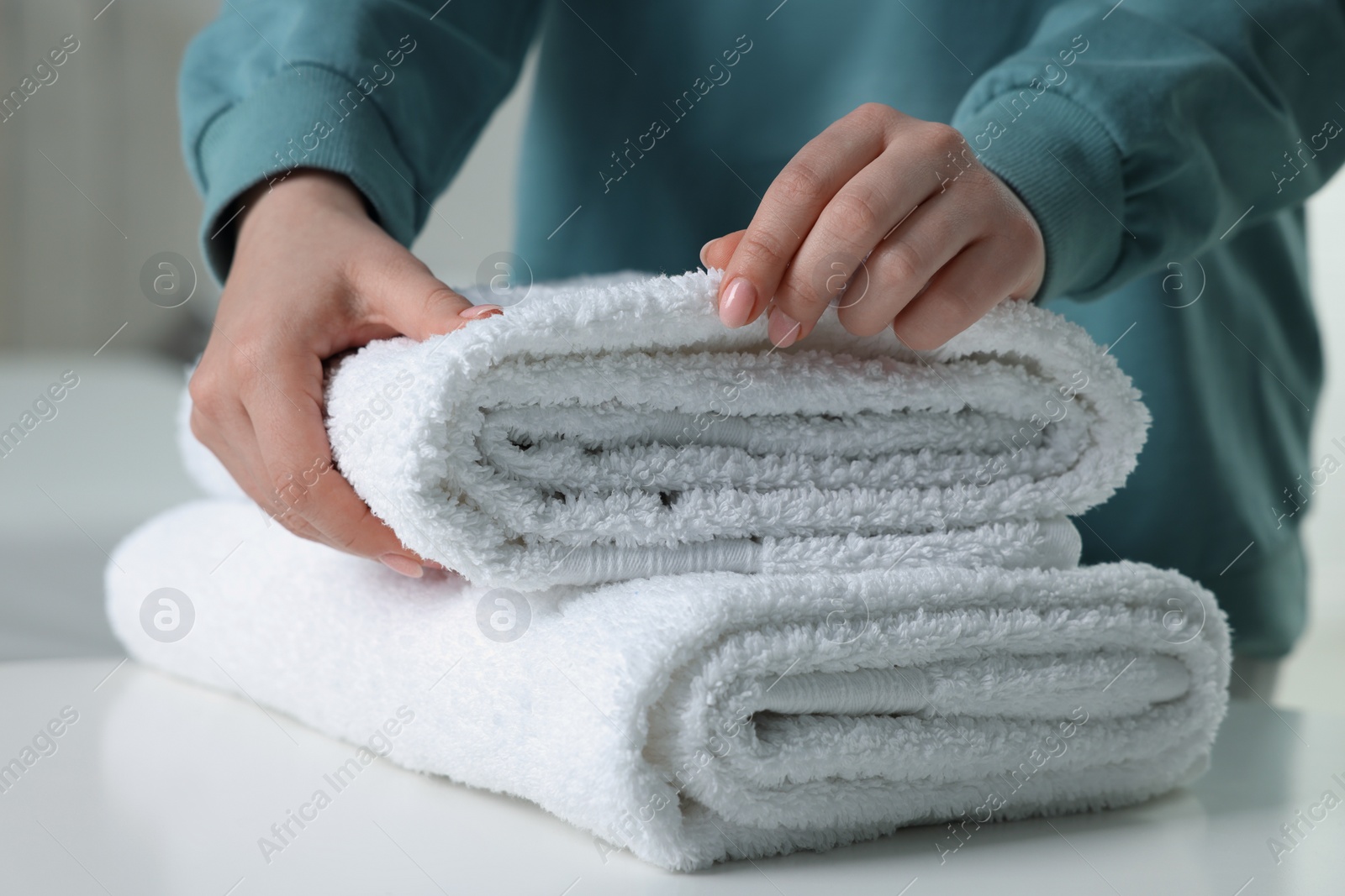 Photo of Woman touching soft white towel indoors, closeup