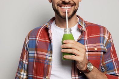 Man drinking delicious juice on grey background, closeup