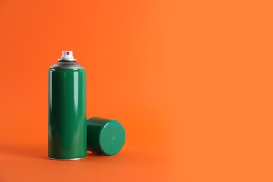 Photo of Green can of spray paint on orange background. Space for text
