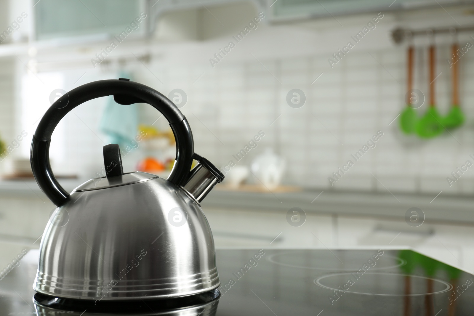 Photo of Modern kettle with whistle on stove in kitchen, space for text