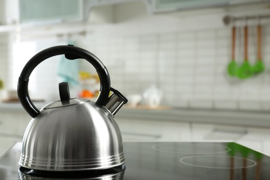 Modern kettle with whistle on stove in kitchen, space for text