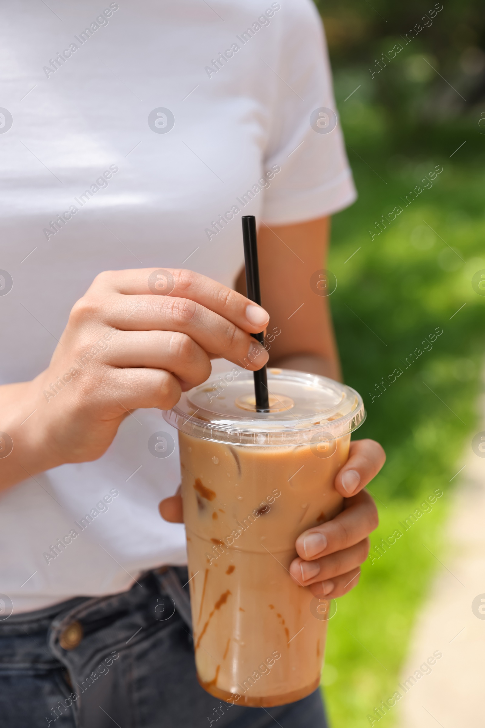 Photo of Woman holding takeaway plastic cup with cold coffee drink outdoors, closeup