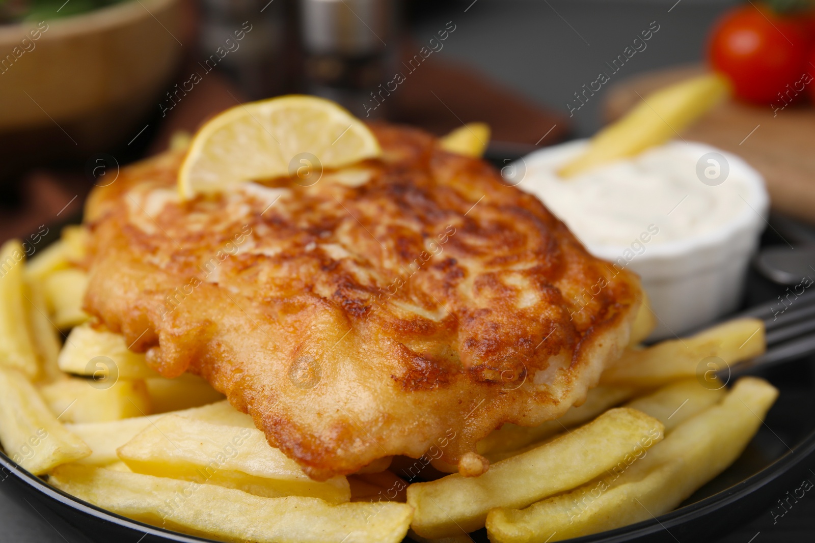 Photo of Tasty soda water battered fish, lemon slice and potato chips on plate, closeup