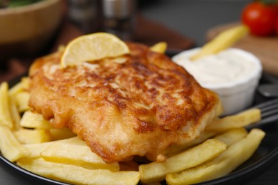 Photo of Tasty soda water battered fish, lemon slice and potato chips on plate, closeup